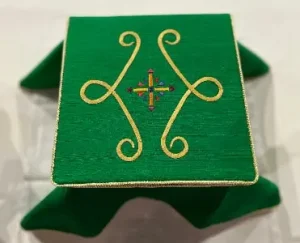 Top view of the burse shows scrollwork and a cross symbol, drawn from the stained glass windows