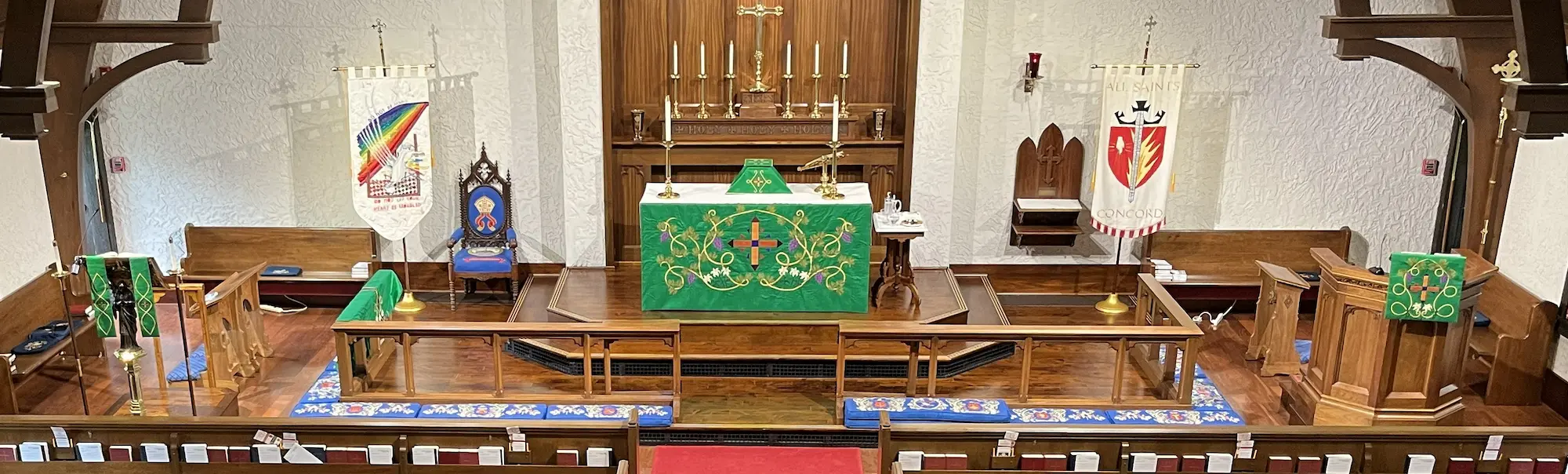 A wide view of the chancel at All Saints in Concord, NC. Shows the lectern stoles, chasuble, altar cloth, original kneelers, and pupit fall