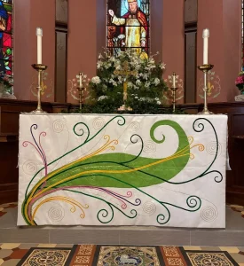 The altar with Easter vestments at Quincy, surrounded by flowers and church architectural details