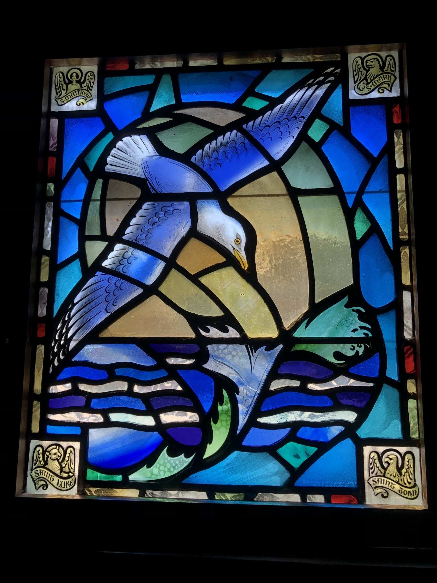 Church window that depicts the ocean and a sea gull in vivid blues, serving as the inspiration for the parament design