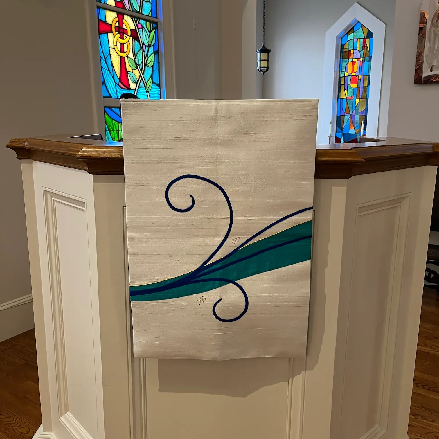 pulpit fall with blue scroll embroidery in church. This piece starts the movement across the sanctuary.